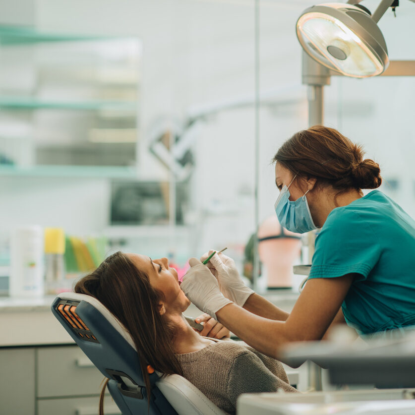 Young woman having her teeth checked during appointment at dentist's office. Female dentist examining young woman's teeth.